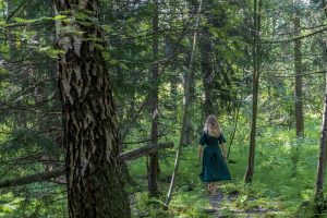 Nainen kävelemässä metsässä.